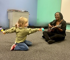 girl plays with maraca with music therapist