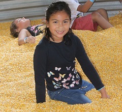 girl plays in corn pit