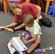 Lekotek leader and child playing game on light board